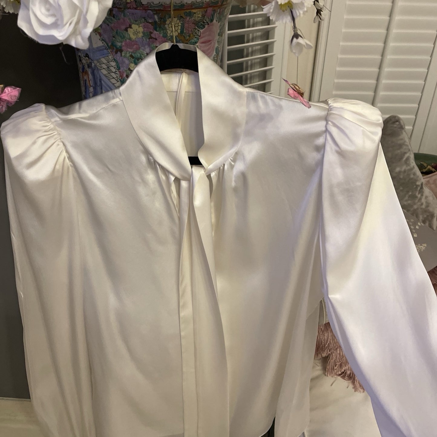 Elegant cream silk blouse by The Vampire’s Wife, featuring a high neck with tie detail, long puffed sleeves, and ruffled cuffs—perfect for designer vintage fashion