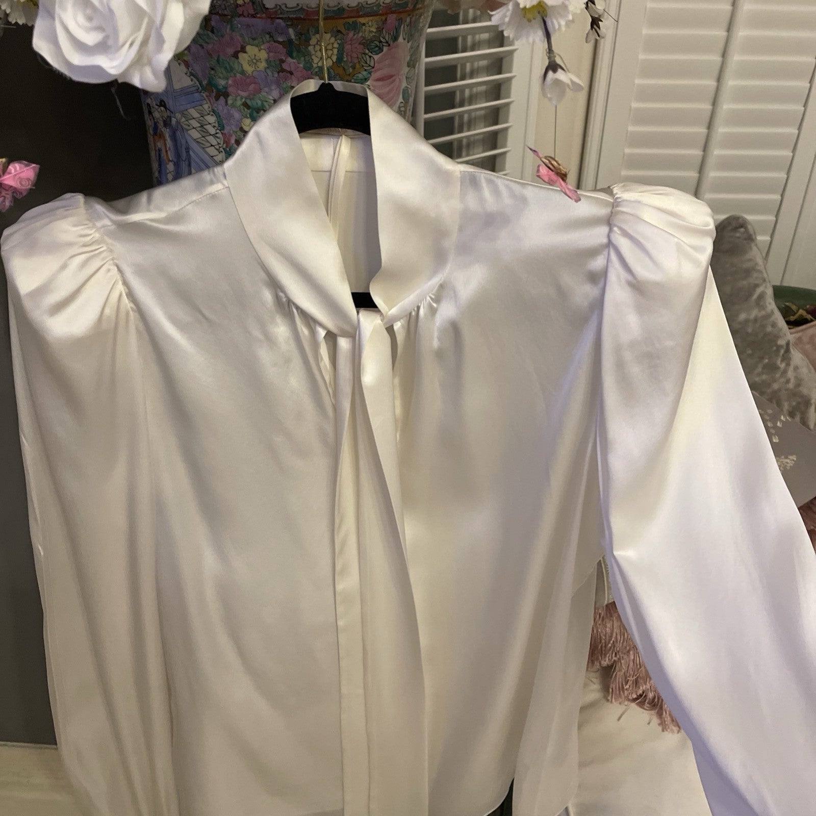 Elegant cream silk blouse by The Vampire’s Wife, featuring a high neck with tie detail, long puffed sleeves, and ruffled cuffs—perfect for designer vintage fashion