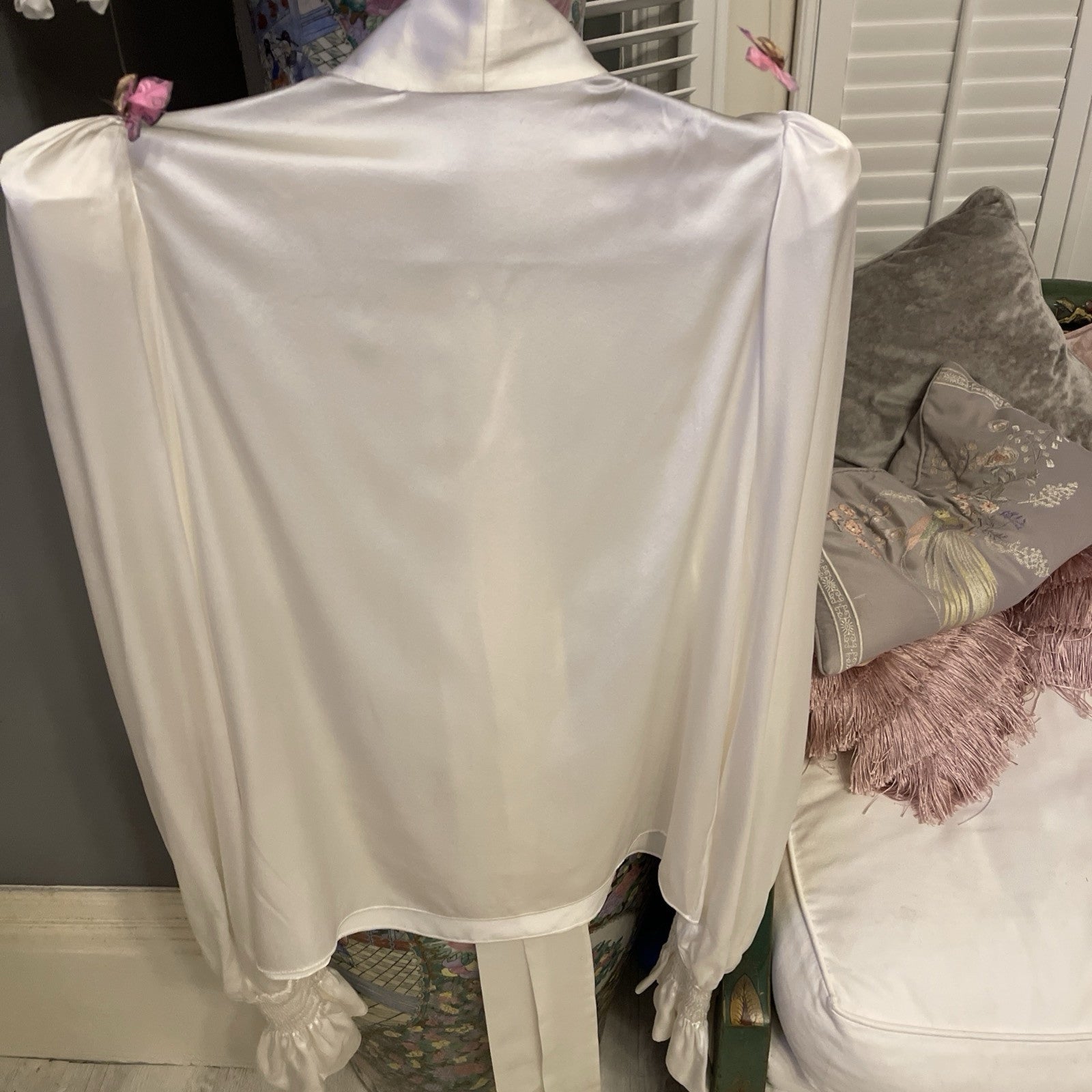 Elegant cream silk blouse by The Vampire’s Wife, featuring a high neck with tie detail, long puffed sleeves, and ruffled cuffs—perfect for designer vintage fashion behind angle