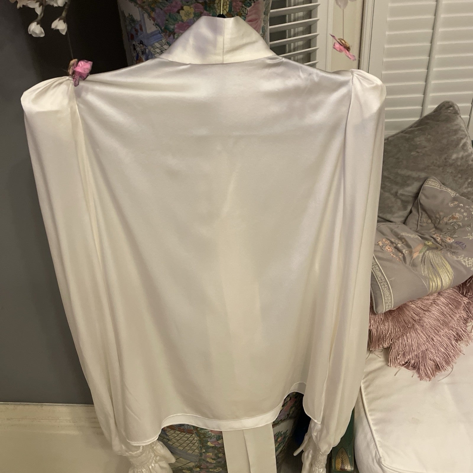 Elegant cream silk blouse by The Vampire’s Wife, featuring a high neck with tie detail, long puffed sleeves, and ruffled cuffs—perfect for designer vintage fashion