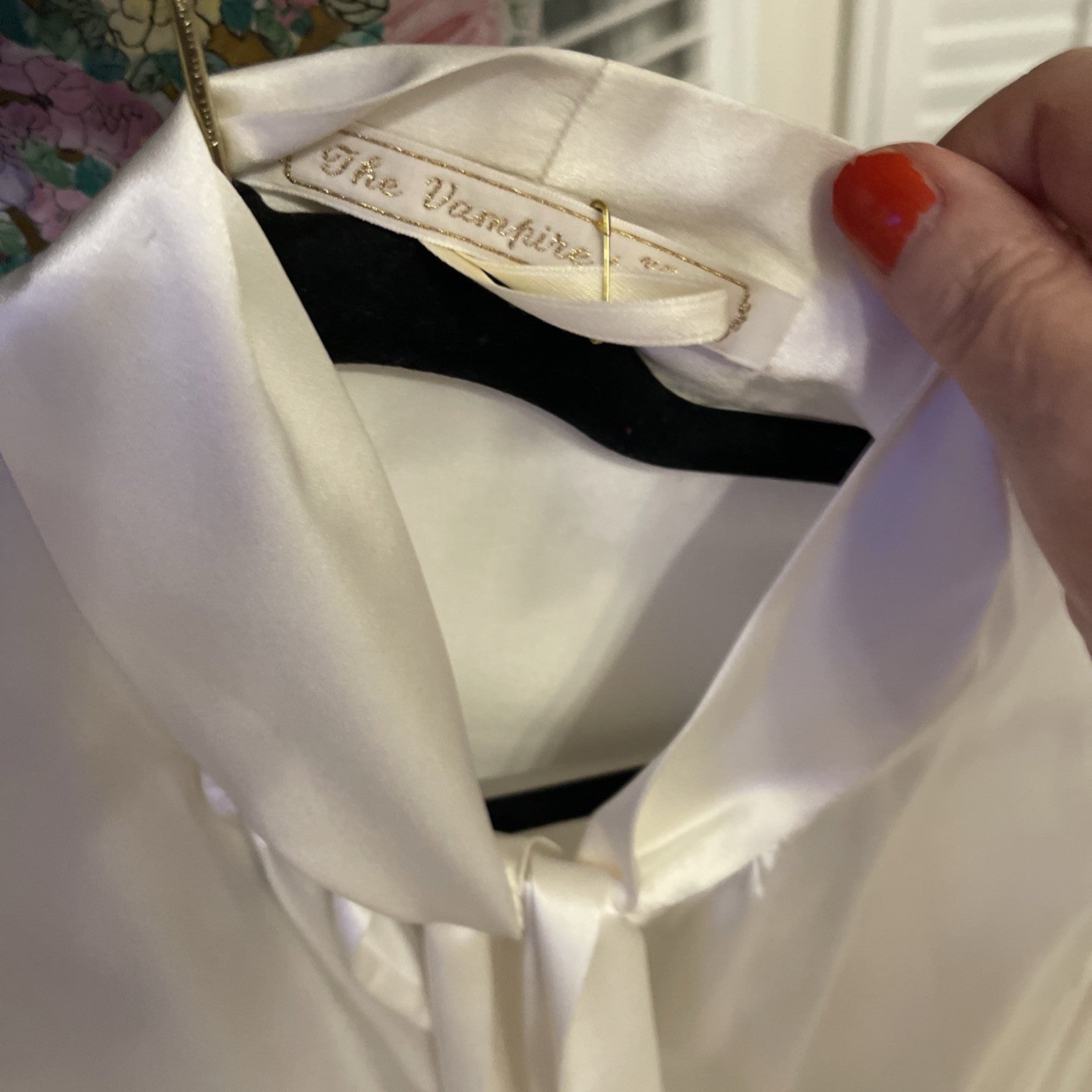 Elegant cream silk blouse by The Vampire’s Wife, featuring a high neck with tie detail, long puffed sleeves, and ruffled cuffs—perfect for designer vintage fashion tag close up
